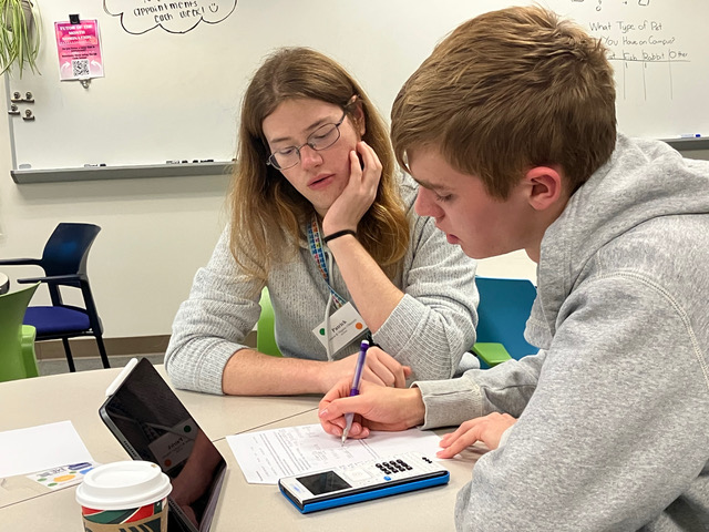 A tutor works through a problem with a student at a table in the Chemistry Success Center.